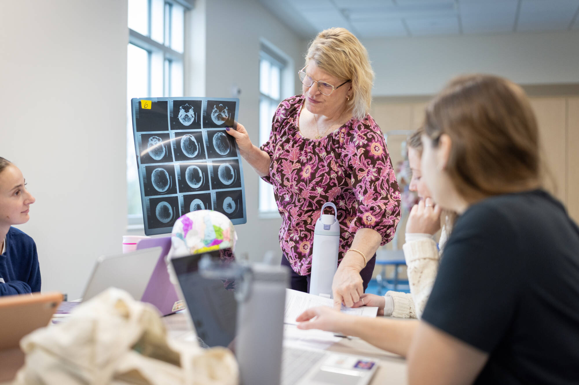 A faculty member reviews skull diagrams with students in a classroom